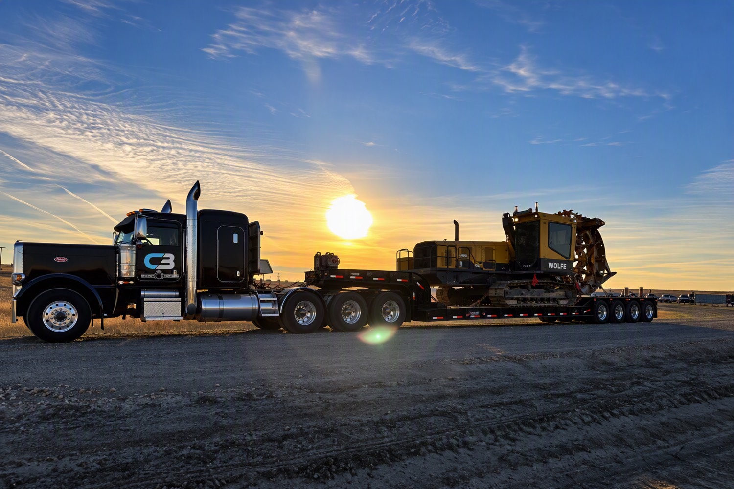 C3 truck hauling a Wolfe trencher at sunset